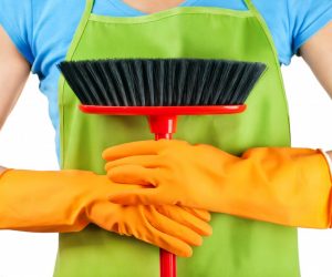 holding a broom with gloves and wearing an apron