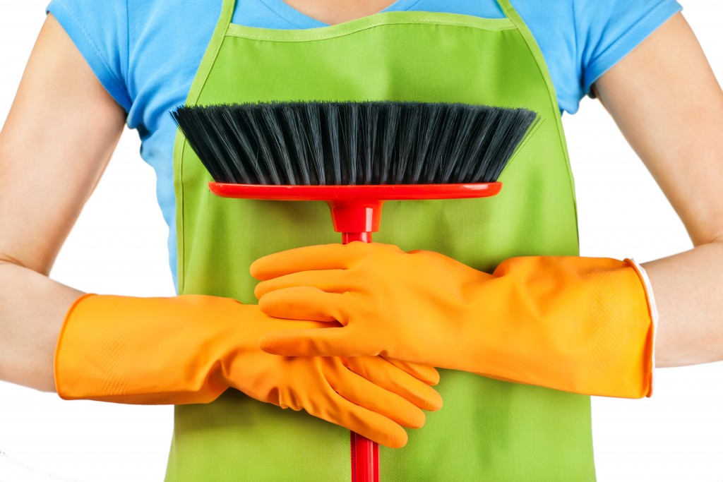 holding a broom with gloves and wearing an apron