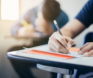 Close up of students writing on a paper