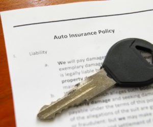 Closeup of a car key on an auto insurance policy