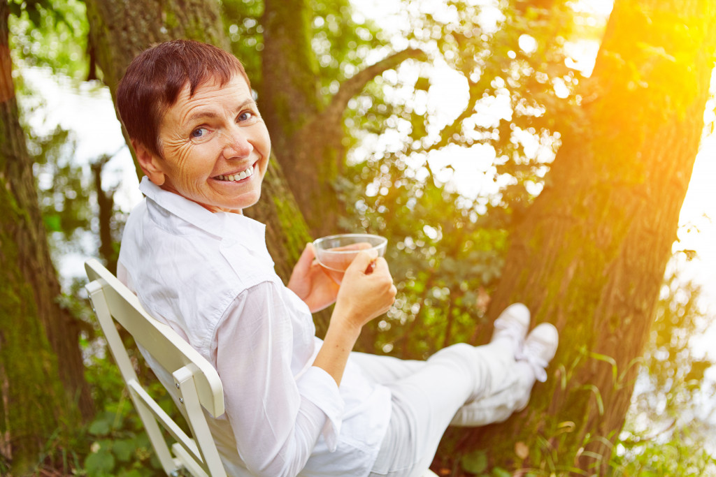 Older woman sitting and drinking tea outdoors