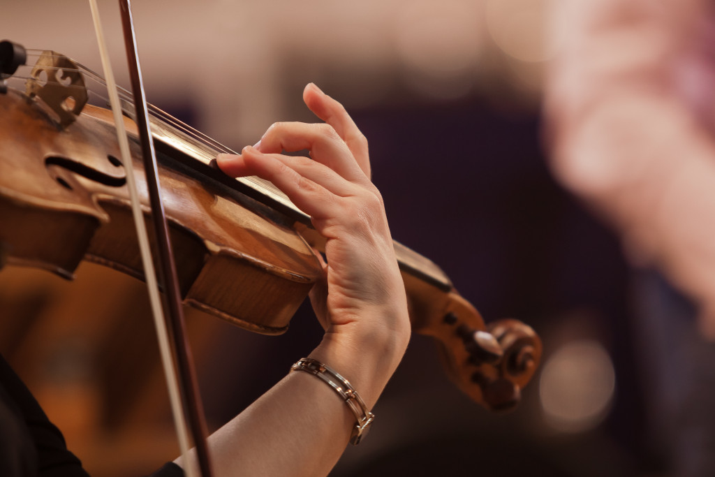 A violinist playing a violin with her fingers and a bow