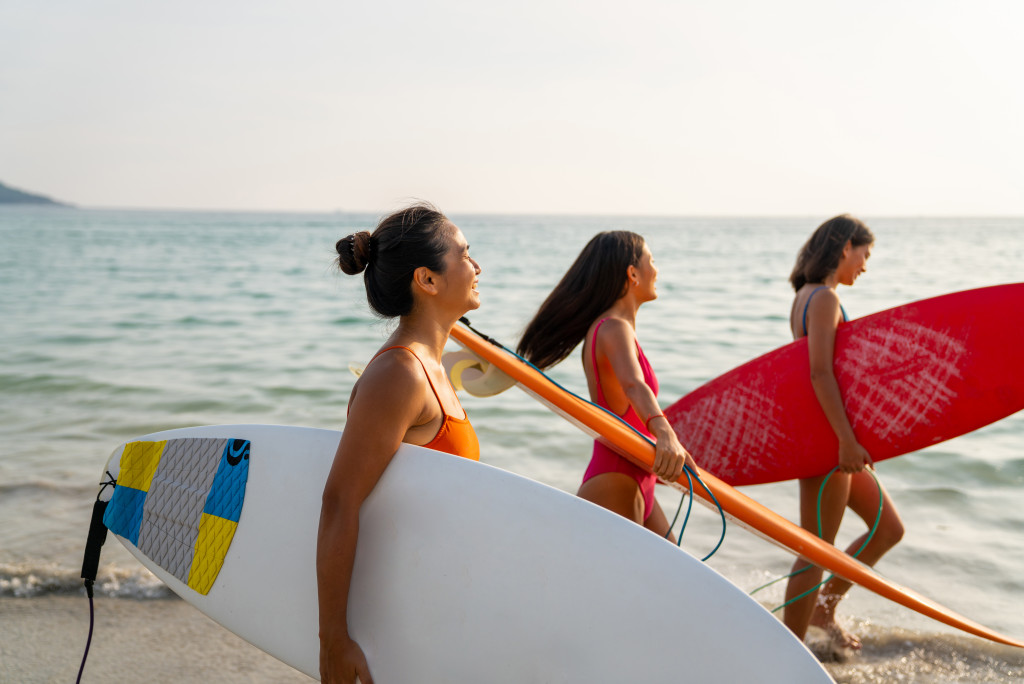 Three women holding surfboards walking on the beach