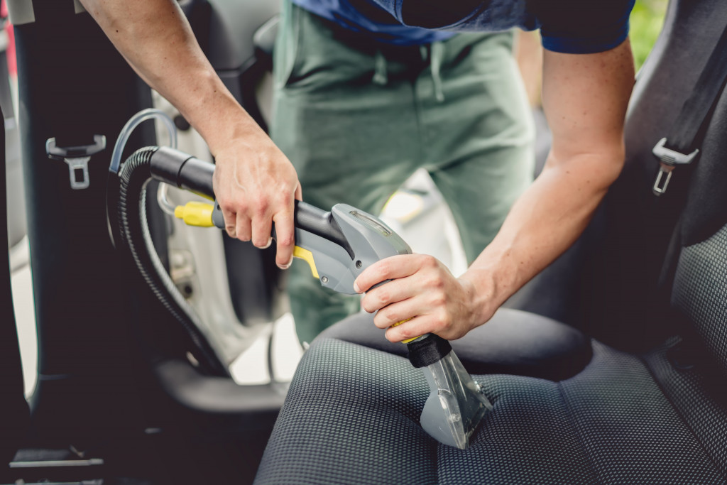 man vaccuuming car seat 