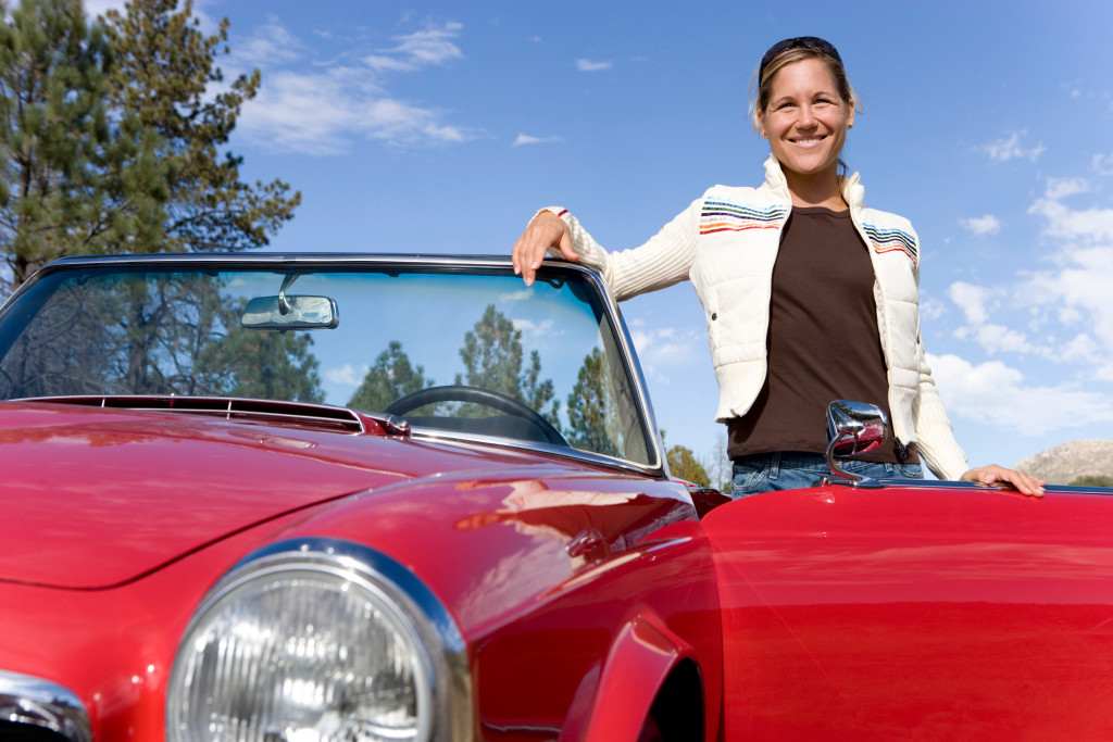 woman smiling standing next to her red sports car