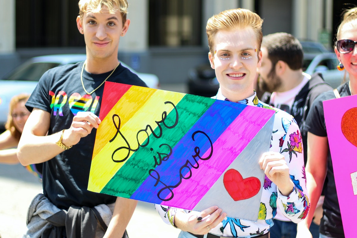 Three Men Holding Assorted Painted Love Is Love Banner