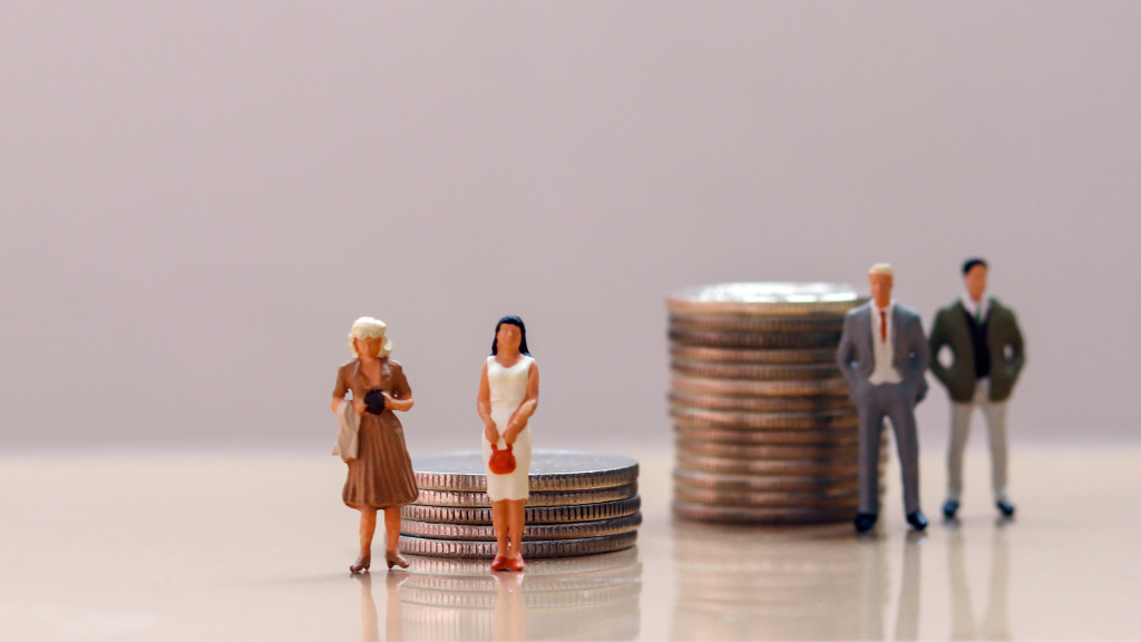 Gender pay gap concept : women in front of a stack of coins and men standing in front of a taller stack of coins