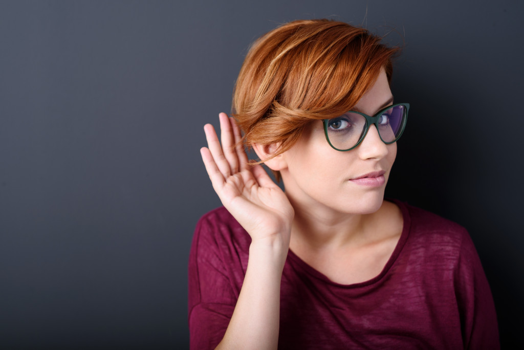 A woman with her hand cupping her ear