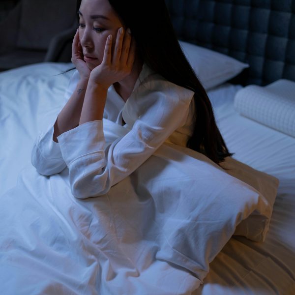 stressed woman sitting in bed, overthinking
