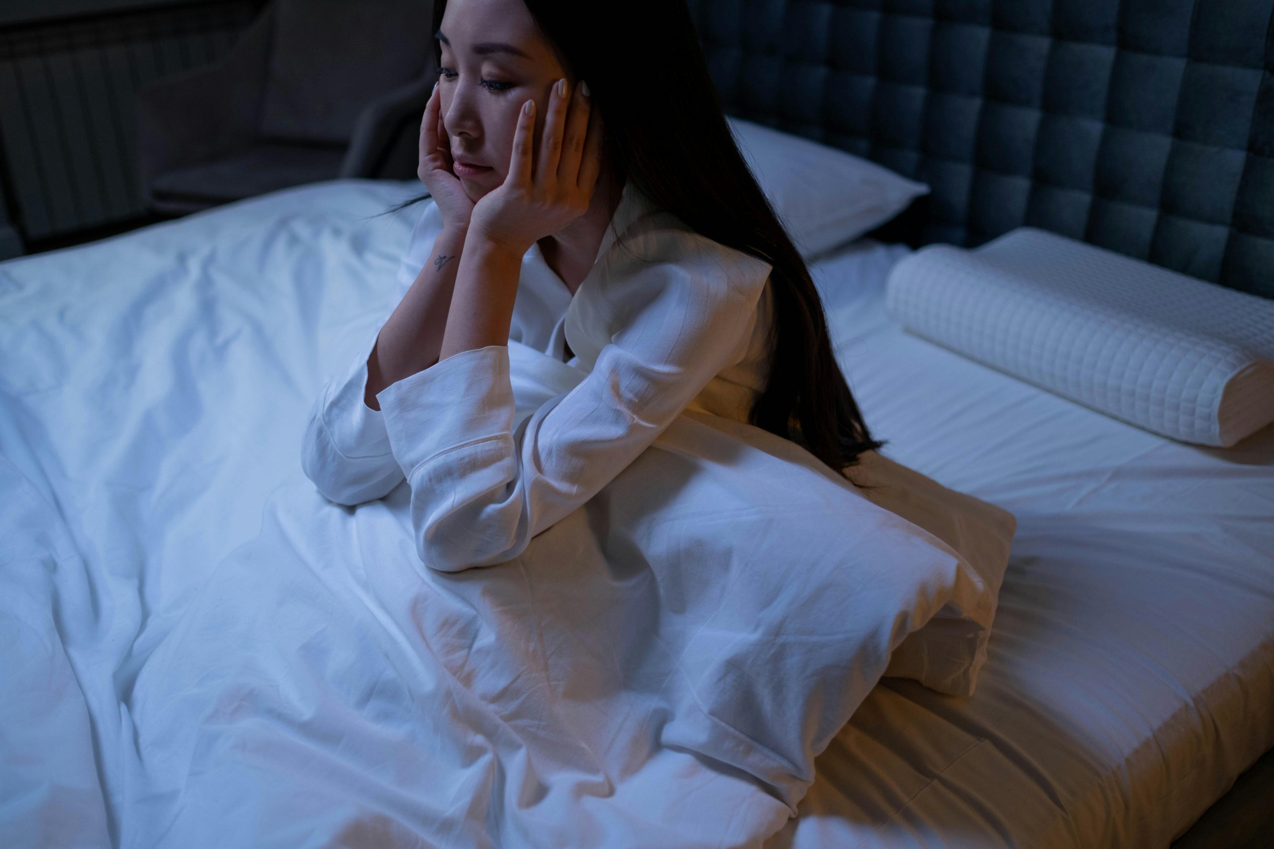 stressed woman sitting in bed, overthinking