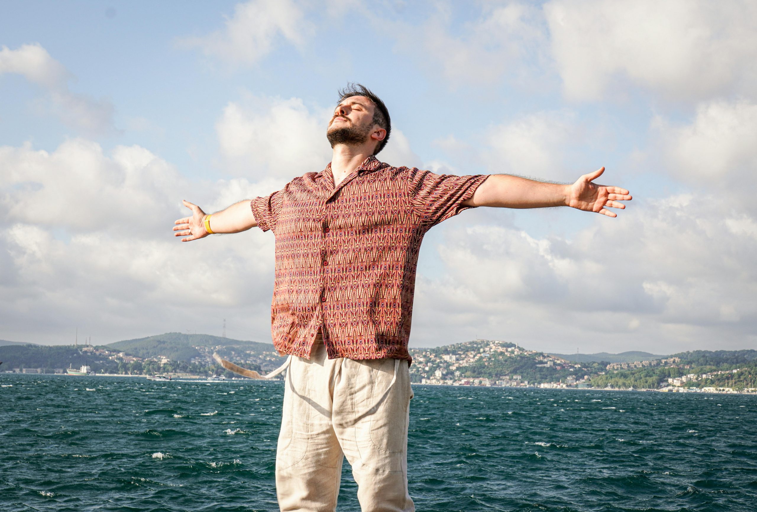 man standing by the sea, with arms wide open